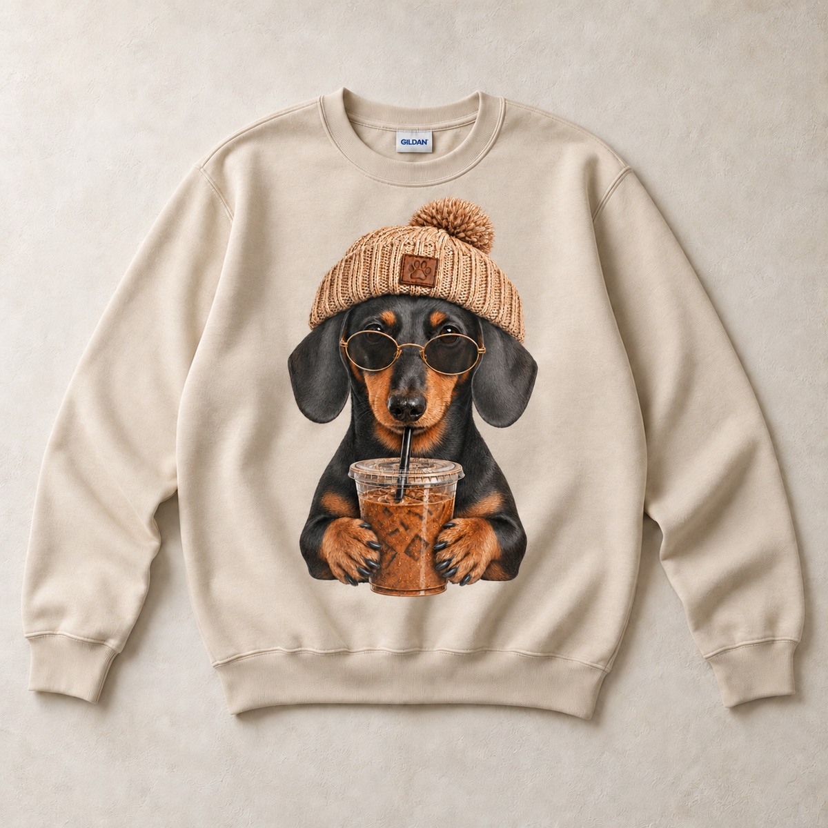 Sand Gildan crewneck sweatshirt with Dachshund Iced Coffee graphic, front flat lay