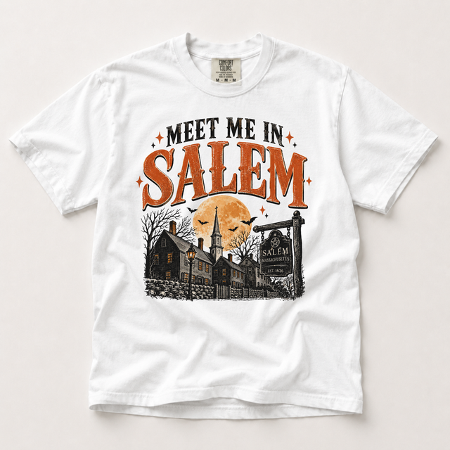 White Comfort Colors Meet Me in Salem Halloween shirt featuring distressed orange and black lettering, a harvest moon, bats and a Salem street scene