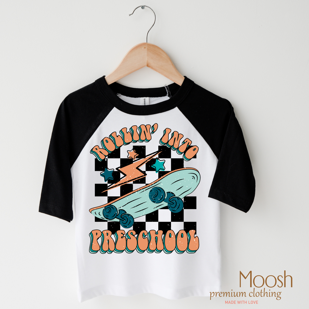 Rollin' Into Preschool Back To School design on a raglan shirt with black sleeves.