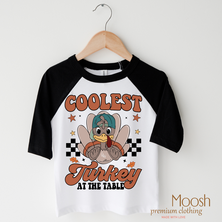 Coolest Turkey At The Table design on a raglan shirt with black sleeves.