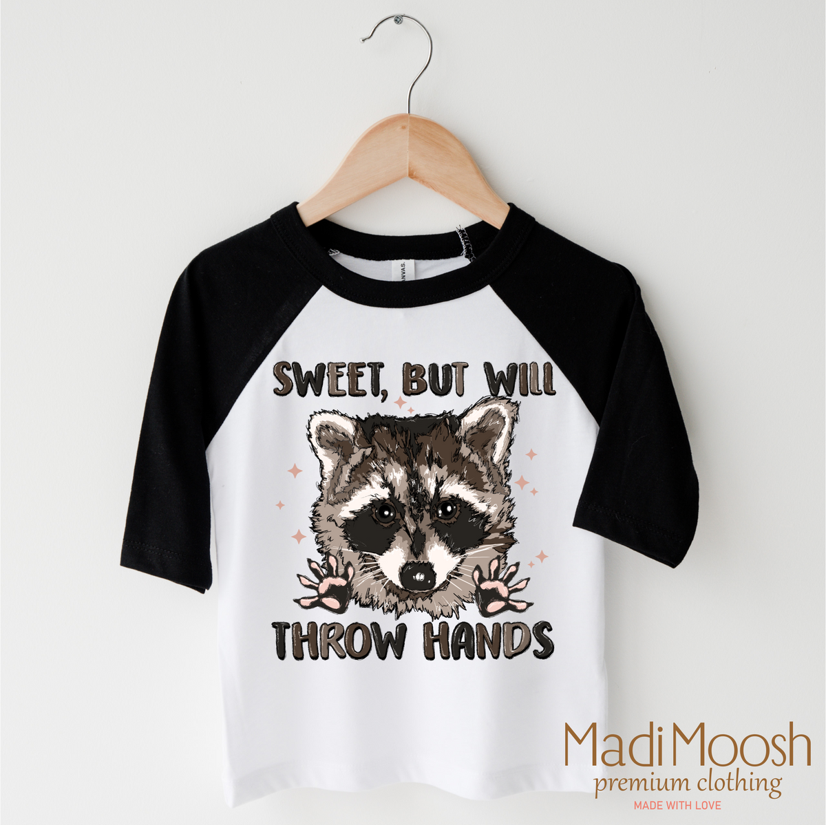 Sweet But I Throw Hands Raccoon design on a black-accented shirt.