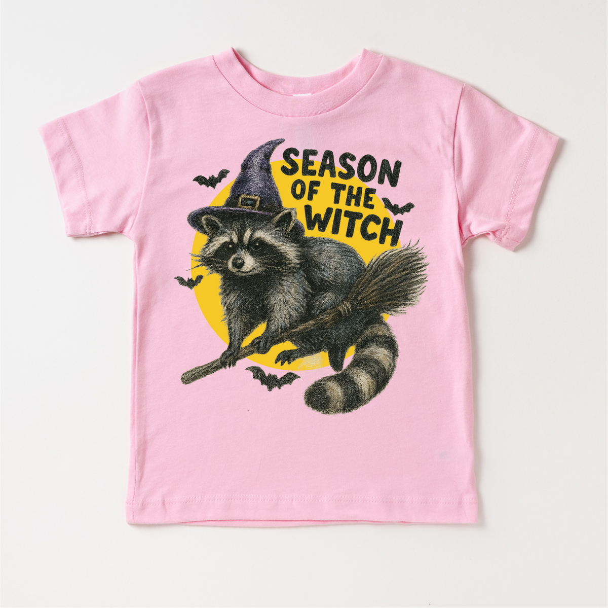 Season Of The Witch Raccoon Halloween design on a pink garment.