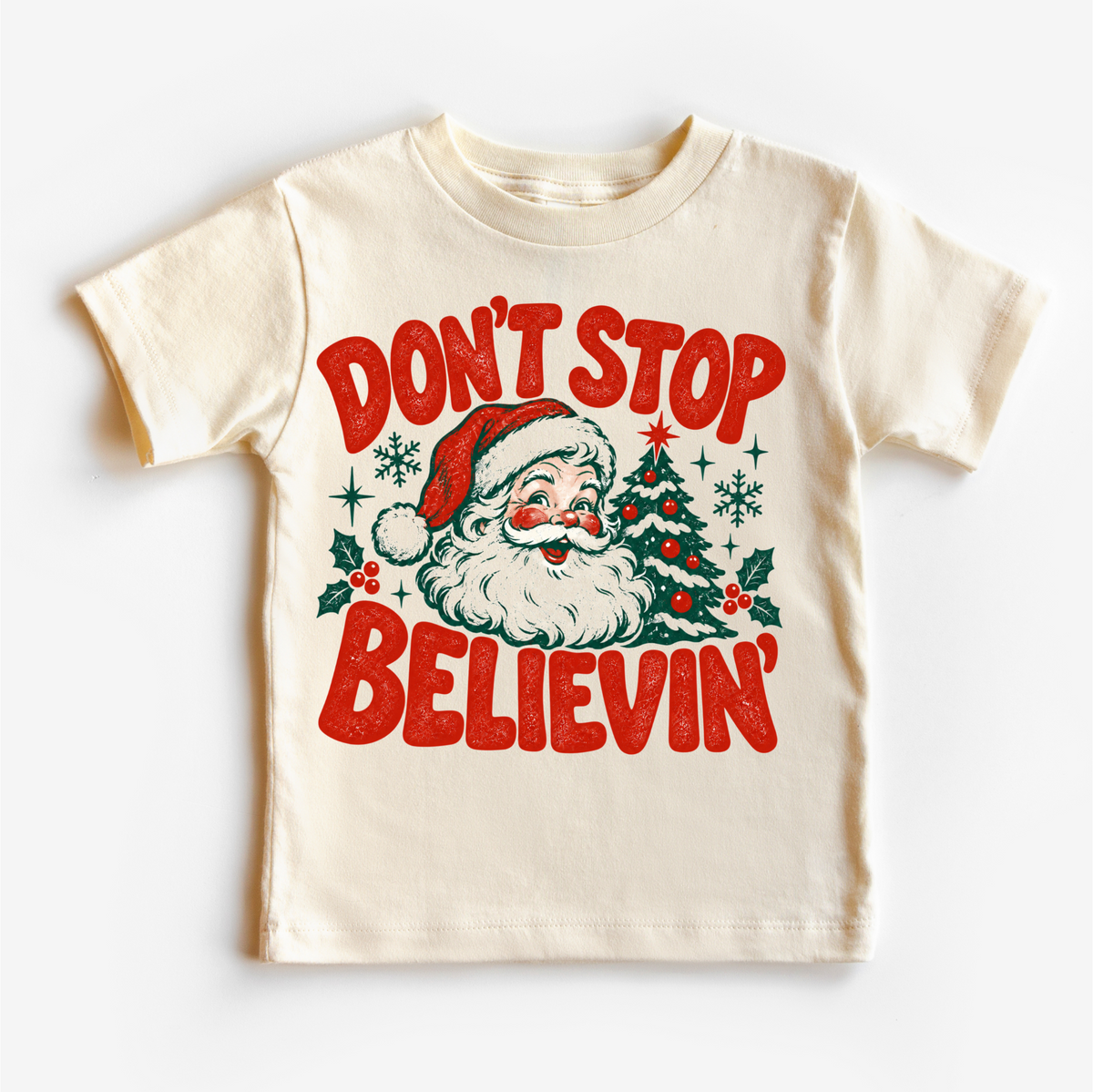 Don't Stop Believin' retro Santa and Christmas tree graphic in red and green on a natural short sleeve tee