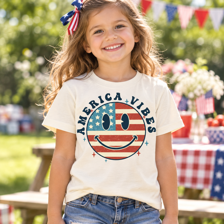 Girl wearing a Natural America Vibes flag smiley face tee at a patriotic summer picnic