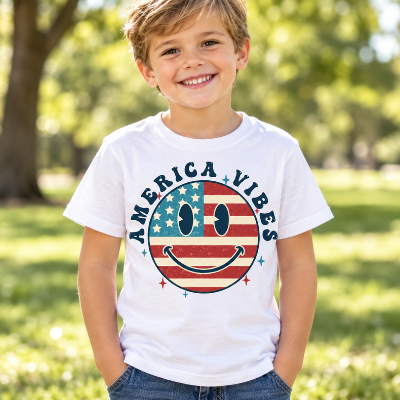 Boy wearing a white America Vibes patriotic flag smiley face shirt outdoors
