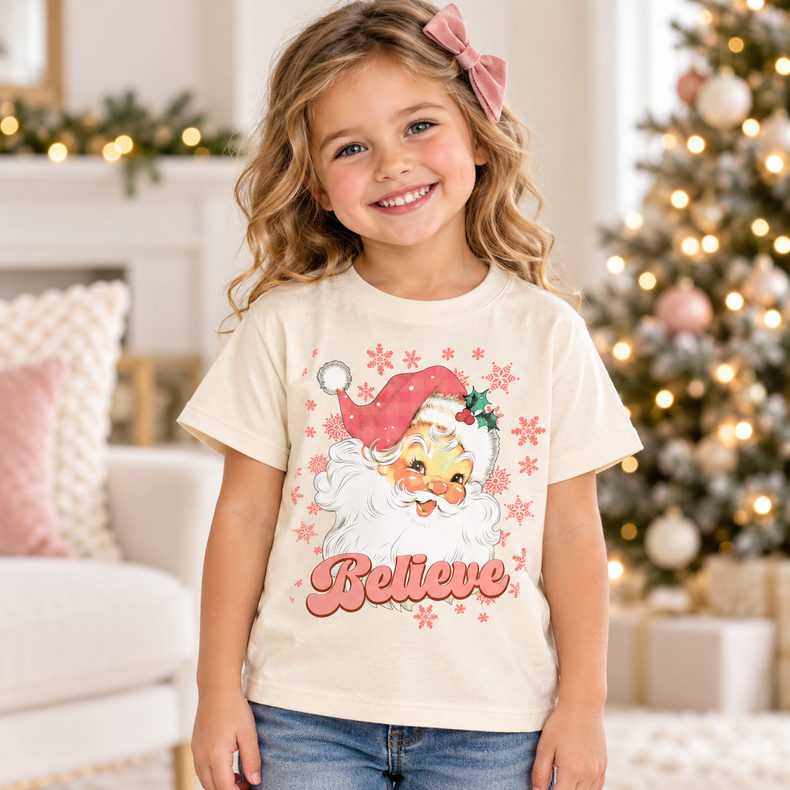 Child wearing natural Santa Claus Believe Shirt in a festive Christmas setting