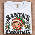 White Comfort Colors Santa's Coming Shirt folded on wood