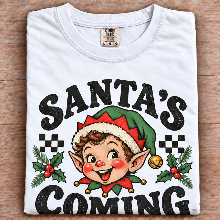 White Comfort Colors Santa's Coming Shirt folded on wood