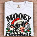 White Comfort Colors Mooey Christmas Shirt folded on wood