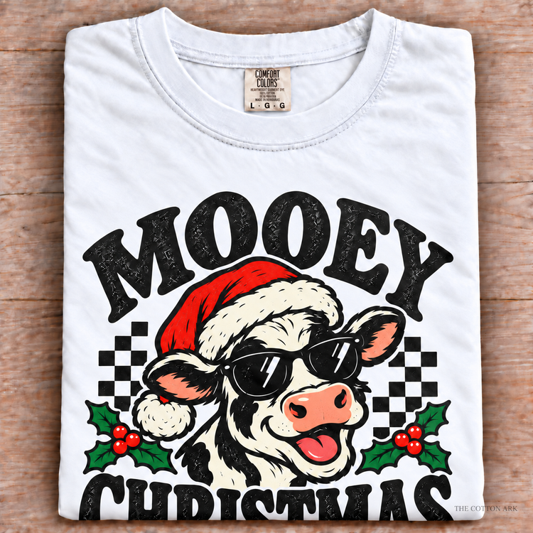 White Comfort Colors Mooey Christmas Shirt folded on wood