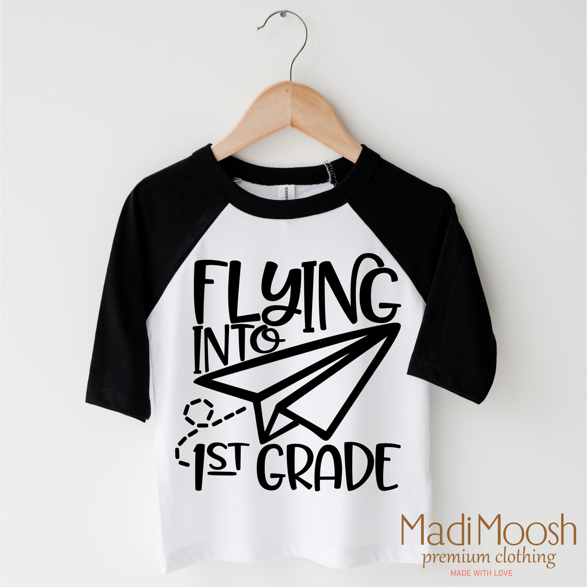 Flying Into First Grade Back To School design on a black-accented shirt.
