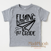 Flying Into First Grade Back To School design on a gray garment.