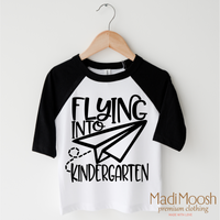Flying Into Kindergarten Back To School design on a black-accented shirt.