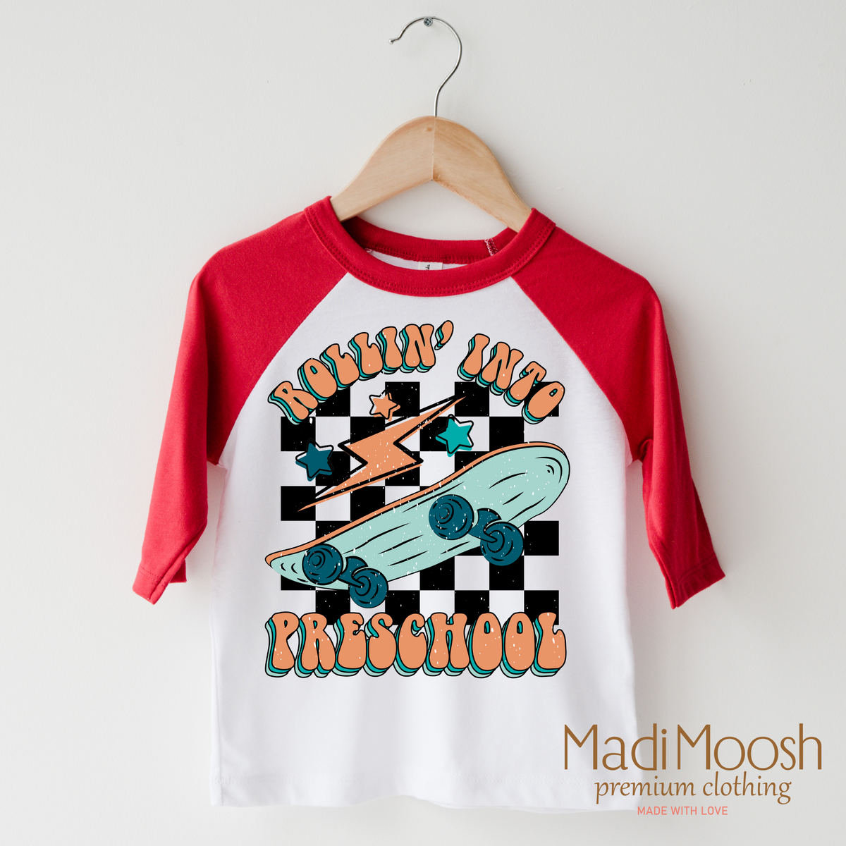 Rollin' Into Preschool Back To School design on a raglan shirt with red sleeves.