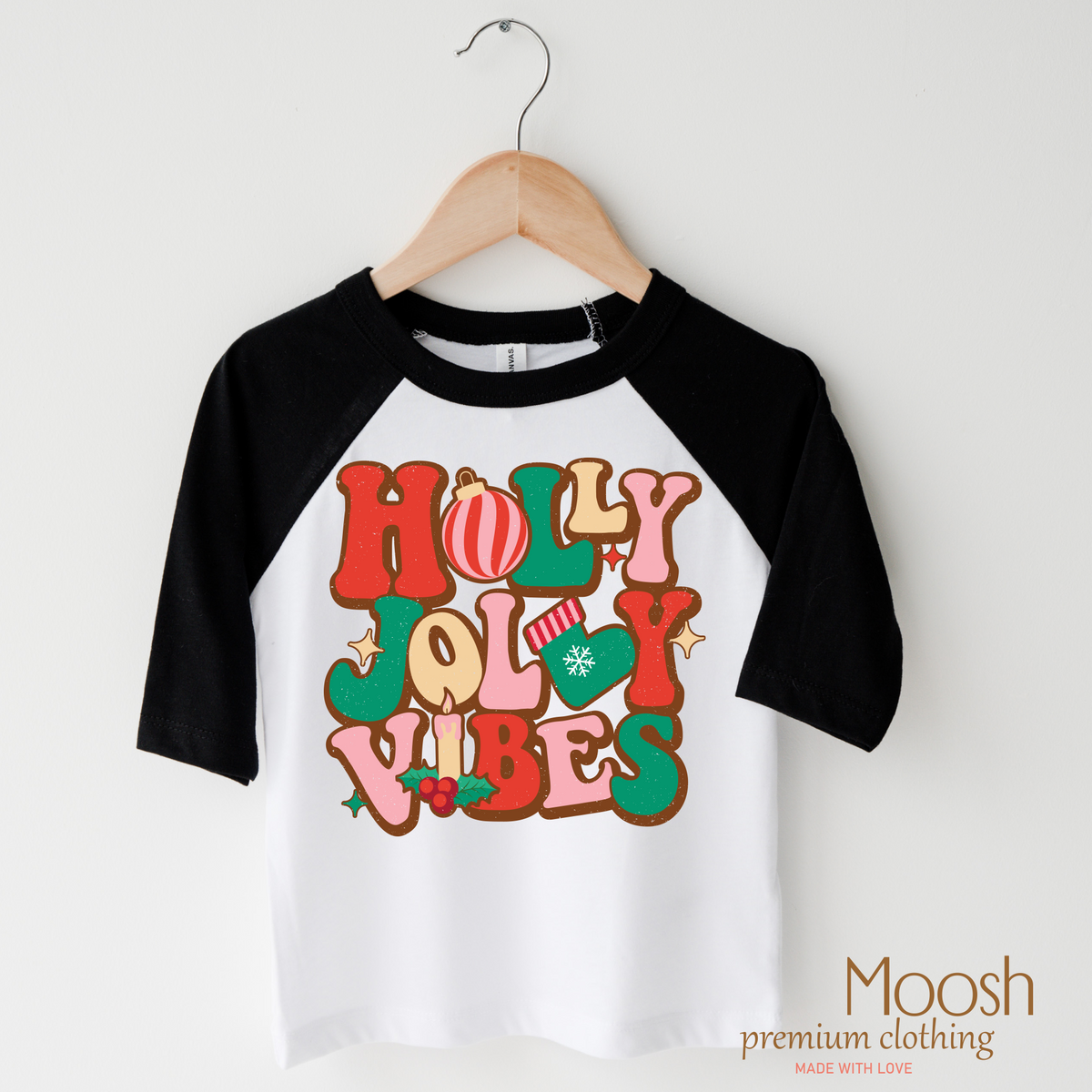Holly Jolly Vibes design on a raglan shirt with black sleeves.