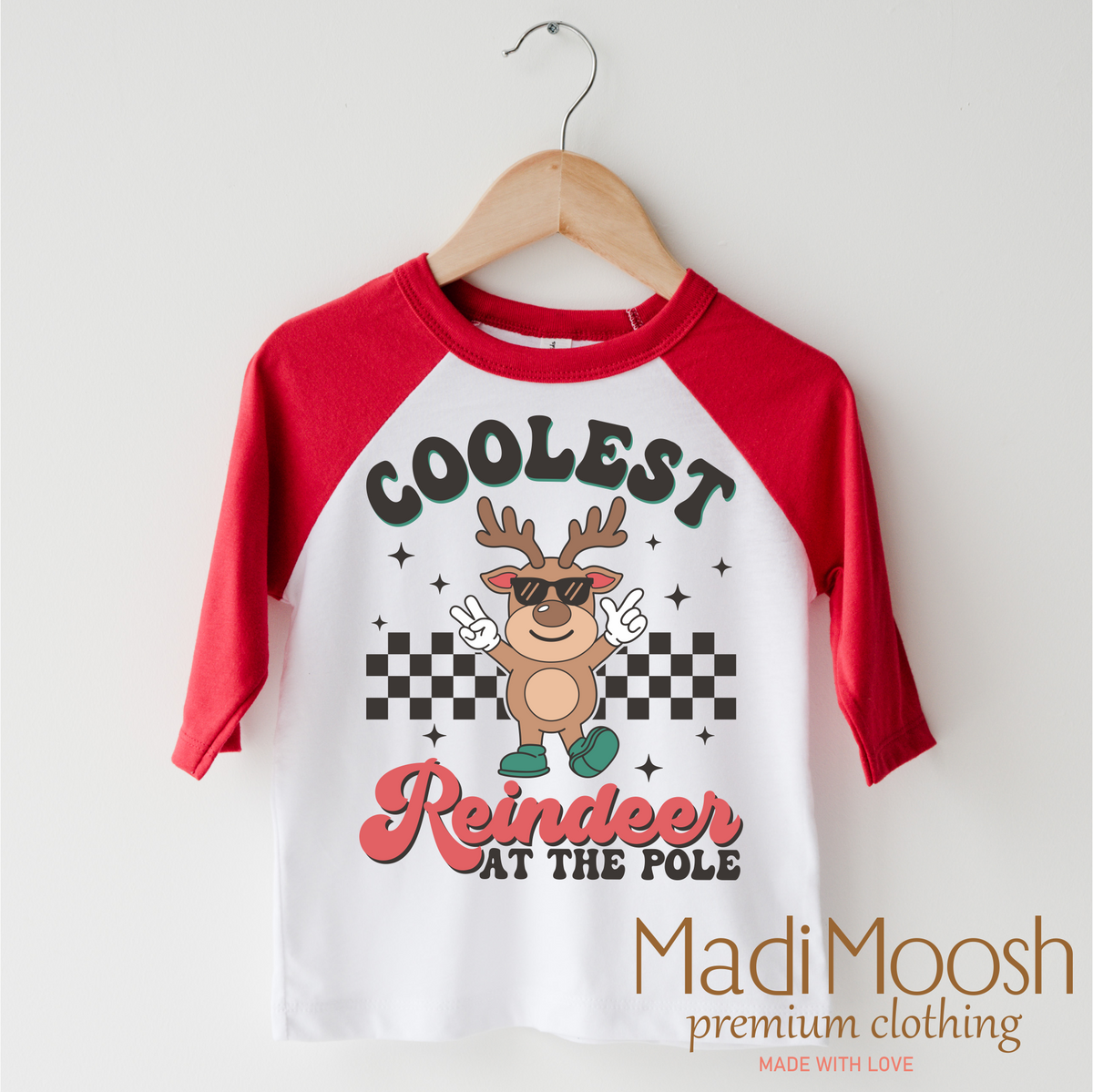 Coolest Reindeer At The Pole Christmas design on a red-accented shirt.