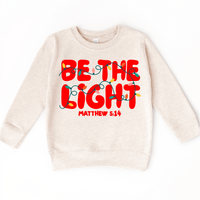Be The Light Christmas Shirt product design and garment details.