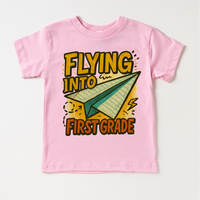 Flying Into First Grade Back To School design on a pink garment.