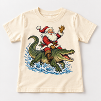 Santa riding an alligator Christmas design on a natural tee by Madi Moosh