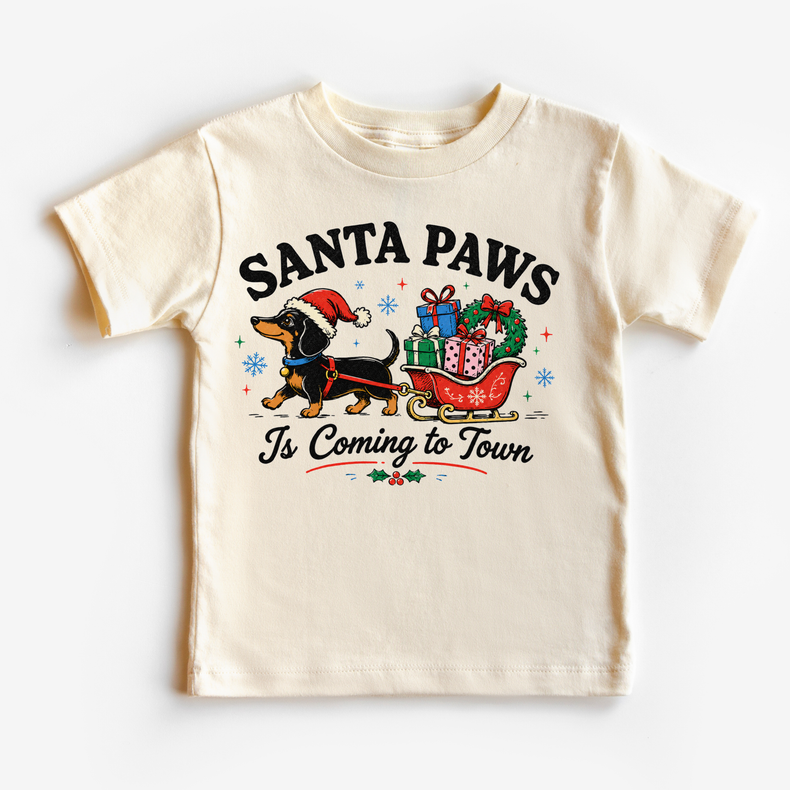 Santa Paws Is Coming to Town natural kids Christmas shirt with a dachshund pulling a sleigh of gifts