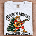 White Comfort Colors Rockin Around the Christmas Tree cowboy Santa shirt folded on wood