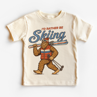 I'd Rather Be Skiing retro Bigfoot carrying skis design on a natural short sleeve tee