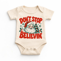 Don't Stop Believin' retro Santa and Christmas tree graphic in red and green on a natural baby bodysuit
