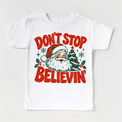 Don't Stop Believin' retro Santa and Christmas tree graphic in red and green on a white short sleeve tee