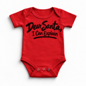 Dear Santa I Can Explain shirt features black brush lettering and a sweeping underline. Shown on red onesie, front view.