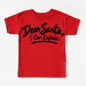 Dear Santa I Can Explain shirt features black brush lettering and a sweeping underline. Shown on red tee, front view.