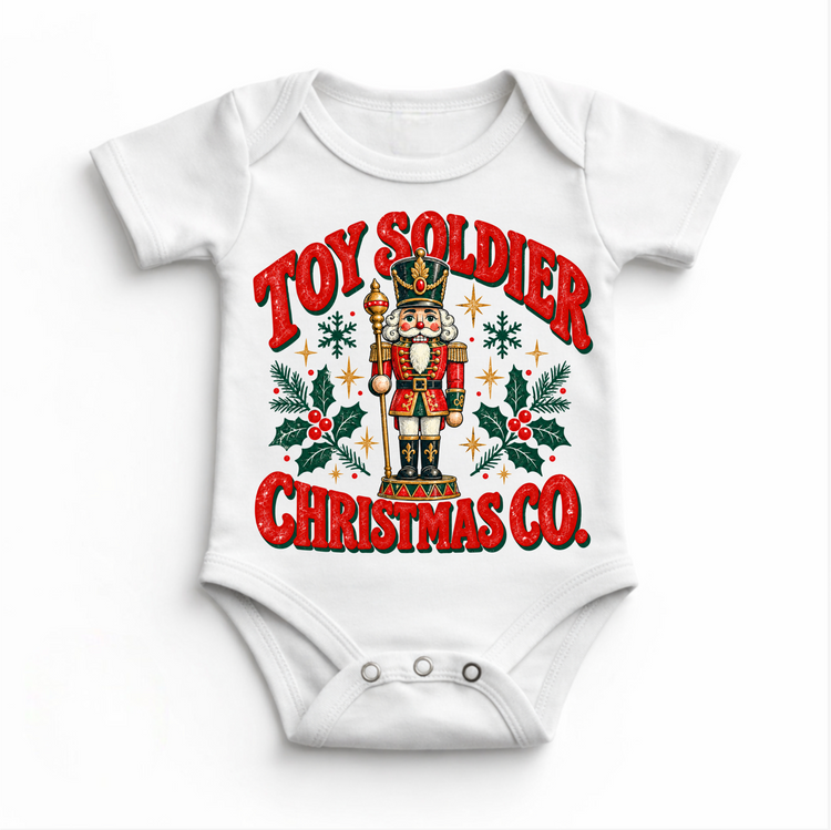 white baby bodysuit with vintage nutcracker, holly and Toy Soldier Christmas Co. lettering