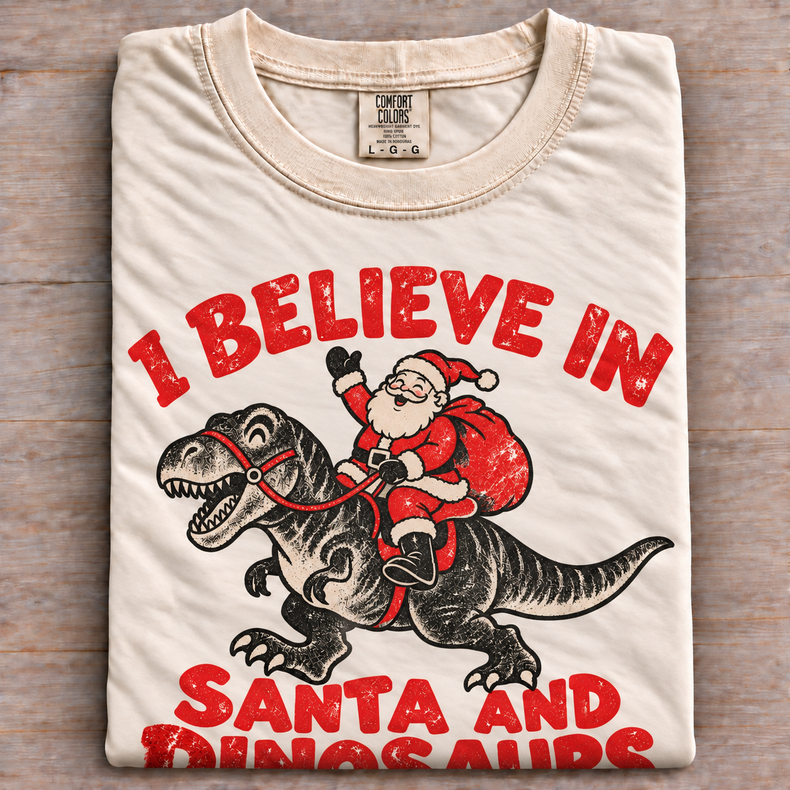 Natural Comfort Colors I Believe in Santa and Dinosaurs shirt folded on wood