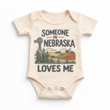 Someone in Nebraska Loves Me design on a natural beige baby bodysuit