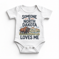 Someone in North Dakota Loves Me design on a white baby bodysuit