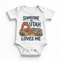 Someone in Utah Loves Me design on a white baby bodysuit