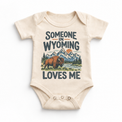Someone in Wyoming Loves Me design on a natural beige baby bodysuit
